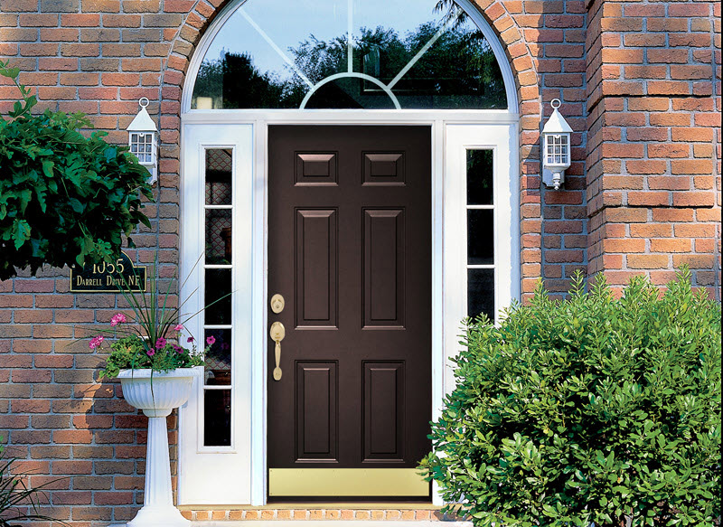 Dark brown steel front door on a brick house with sidelites and transom window above.