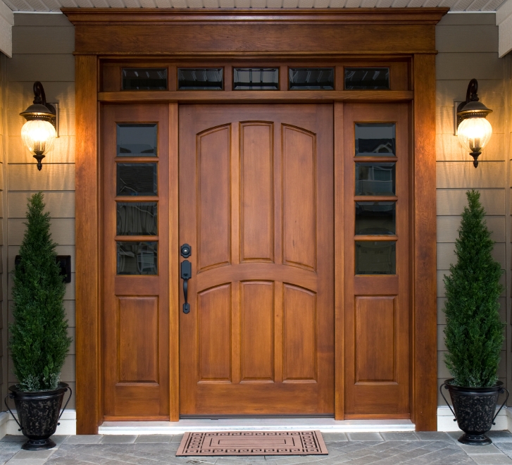 Large wooden front entry door with transom windows on the side and across the top