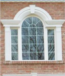 Paneled arch window with a white frame on a brick house