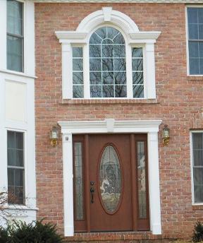Two story brick house with a brown door with an arched window above it