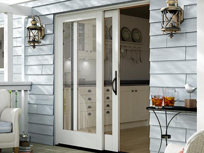White sliding glass doors with black handle, door partially open, leading from a deck to a kitchen inside.