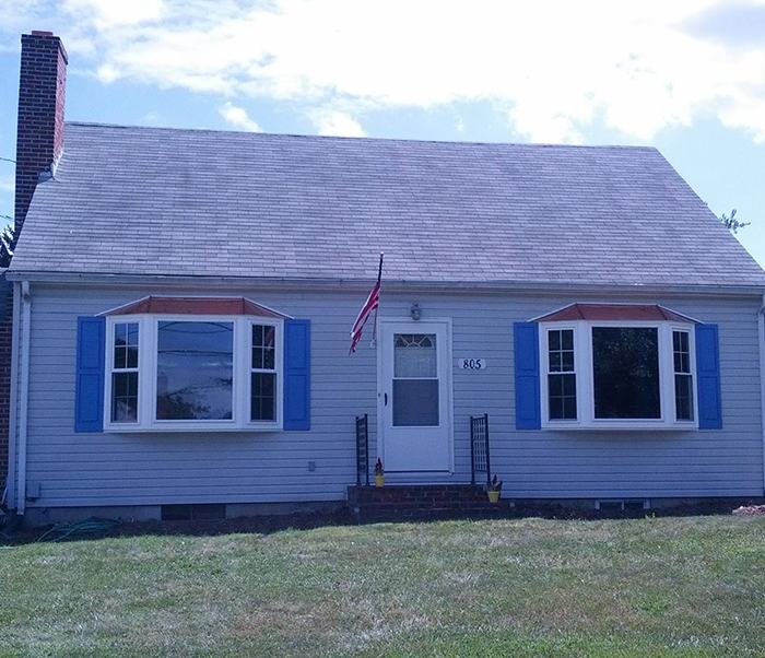 Light blue house with two front bay windows and a white door