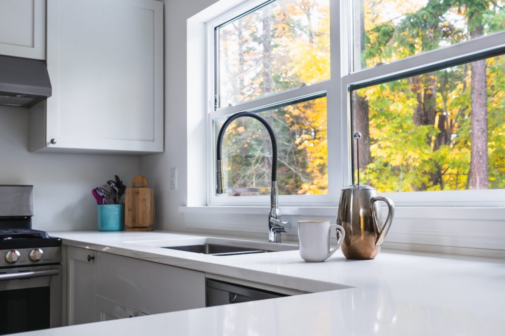 Double-hung windows above a kitchen sink and white stone countertop.
