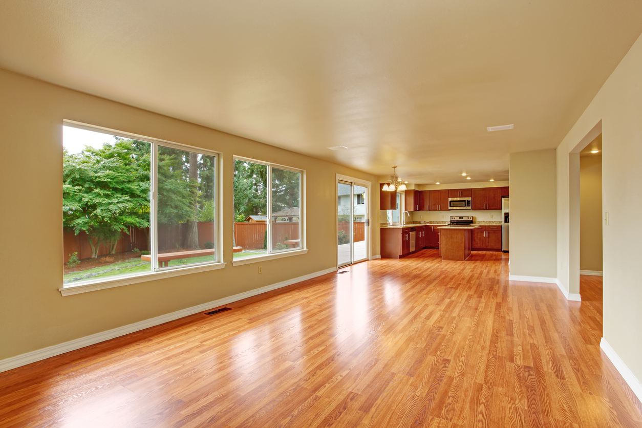 Two large sliding windows and sliding glass door in empty living room with wood floor